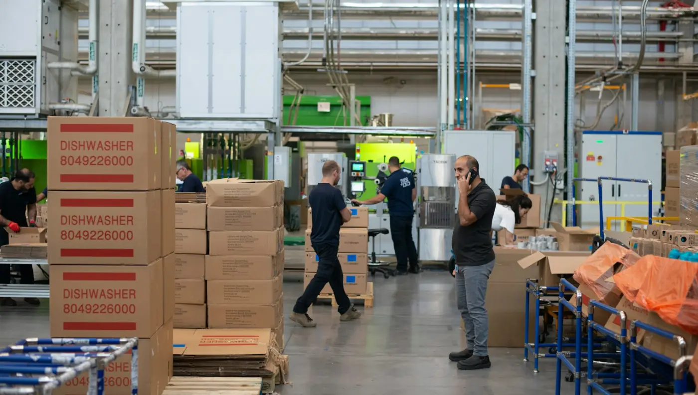 Workers moving boxes between pallets on a busy warehouse floor